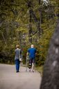 Back view of unrecognizable male in orthosis on broken leg walking with woman on path in park