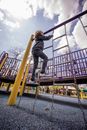 From below full body of curious child climbing on suspended metal ladder on chains on playground