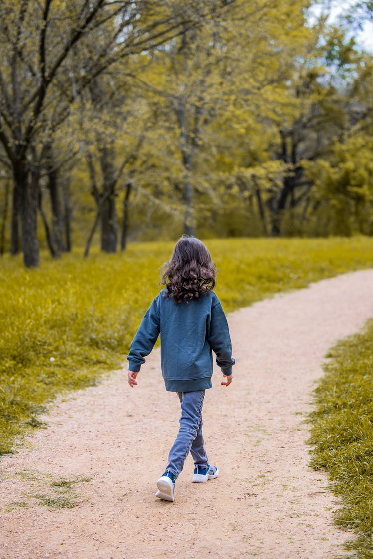 Unrecognizable Girl Walking On Curved Path In Park