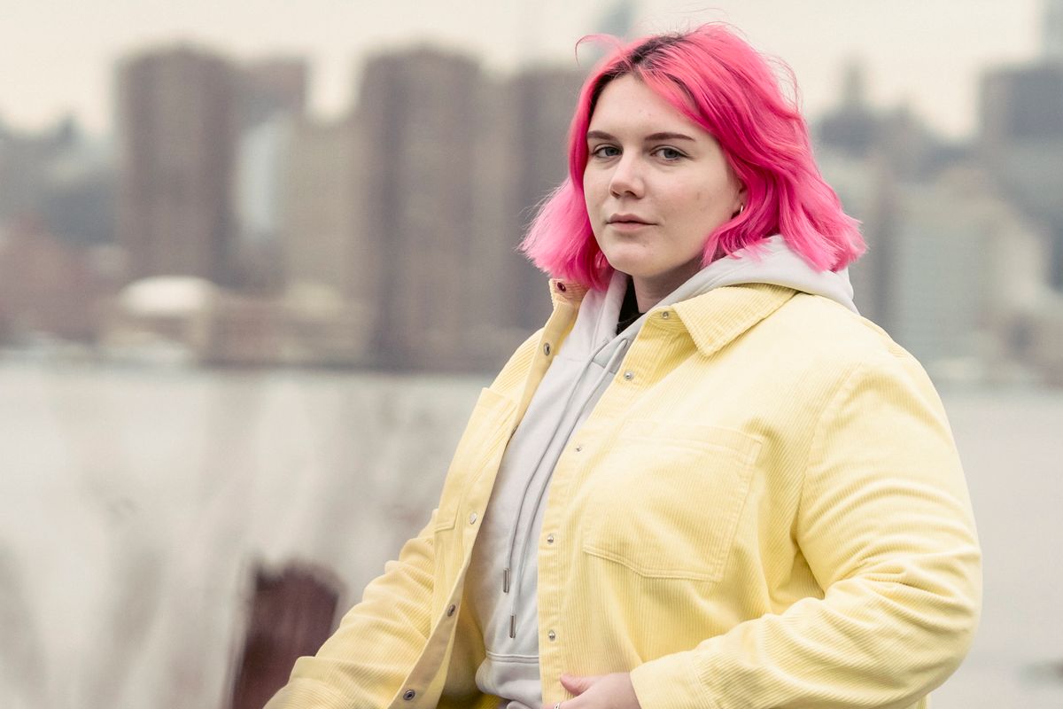 Woman with bright pink hair wearing a yellow jacket