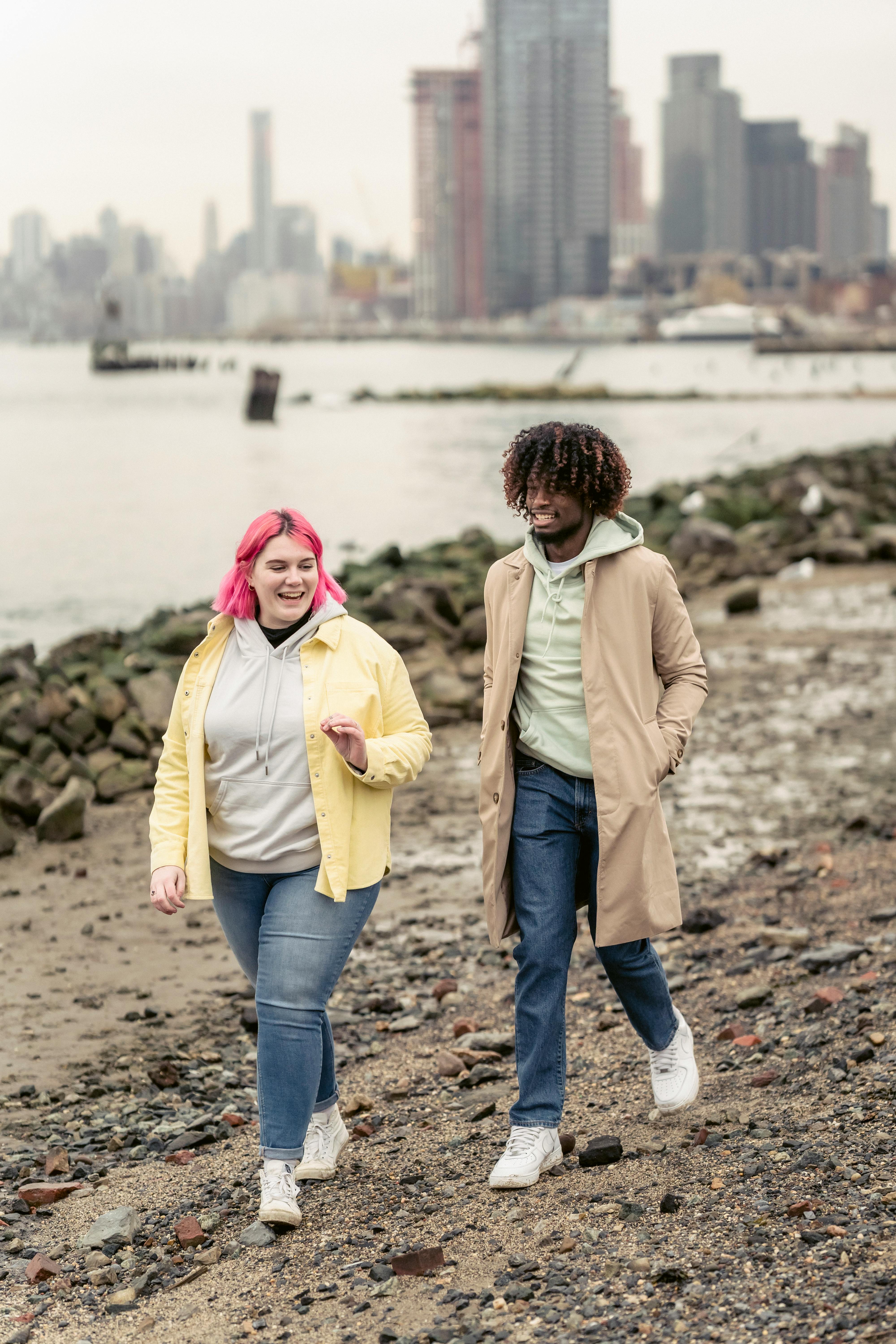 positive diverse couple walking on embankment