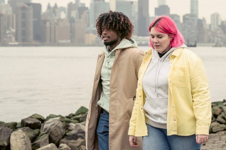 Multiracial Couple In Outerwear Walking Near River