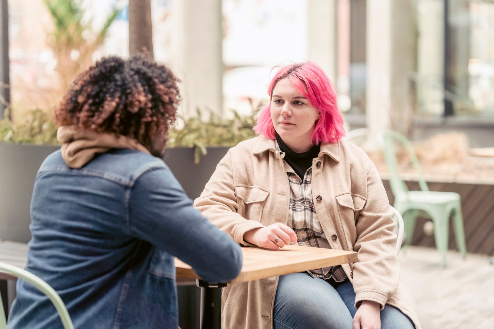 Two friends having a conversation at an outdoor cafe table