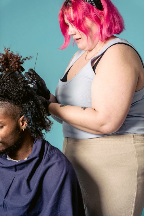 Free Side view of professional hairdresser in black gloves coloring hair with brush to African American male client against blue background Stock Photo
