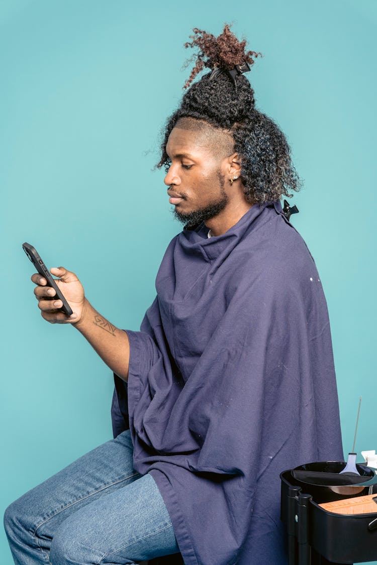 Serious Black Man Using Smartphone In Hairdressing Studio