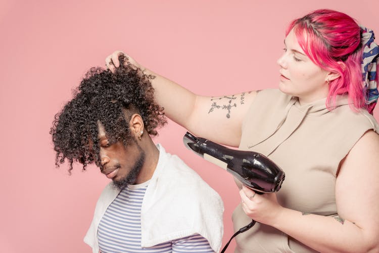 Focused Woman With Hair Dryer Doing Hairdo For Black Client