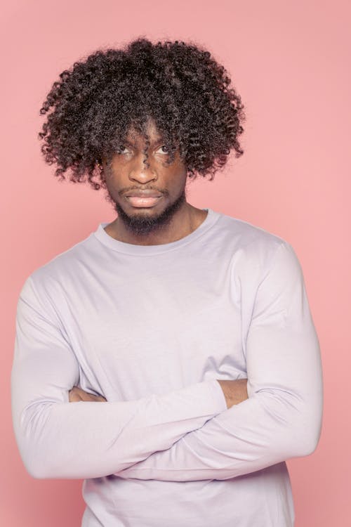 Confident black man with Afro hairstyle against pink wall