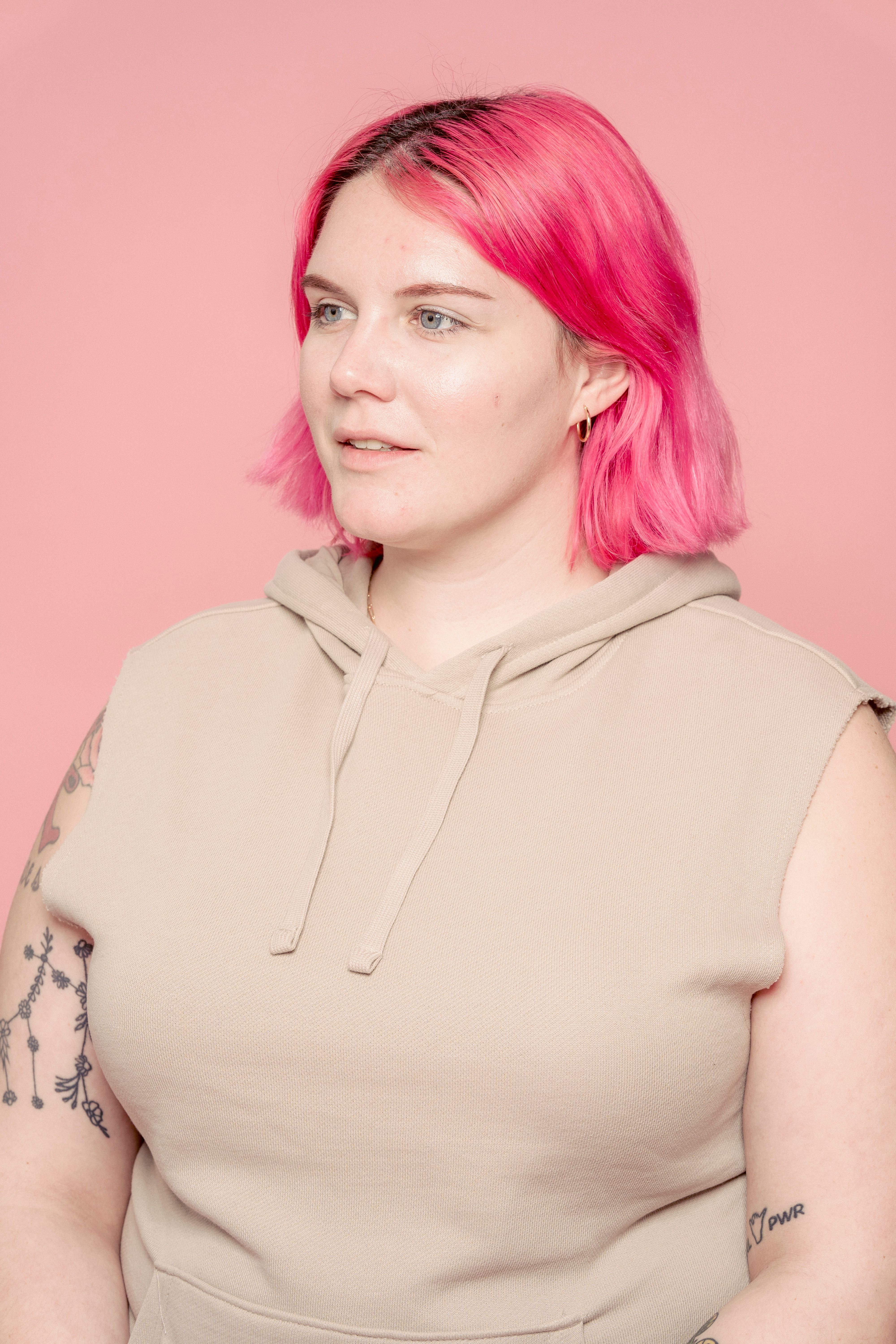 Smiling plus size female model wearing casual outfit looking away against pink background