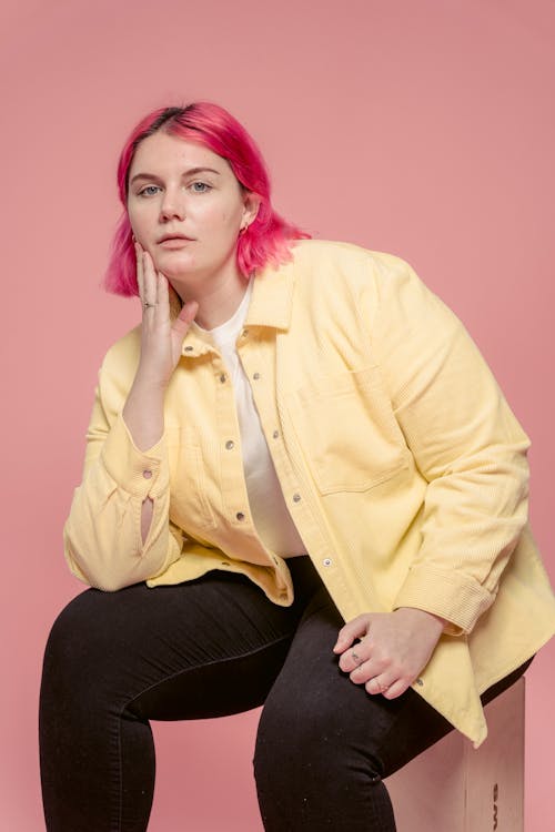 Serious woman touching face while sitting in studio