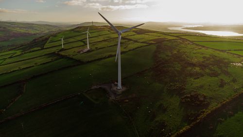 Free Scenic aerial view of wind turbines in rolling green fields at sunset, promoting renewable energy and sustainability. Stock Photo