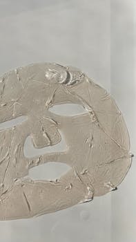 A close-up of a textured face sheet mask on a smooth, white surface.