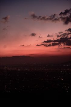 A breathtaking sunset casting vibrant hues over a cityscape, highlighting silhouetted mountains.