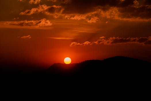 A breathtaking sunset with a vibrant orange sky and mountain silhouette, capturing nature's beauty.