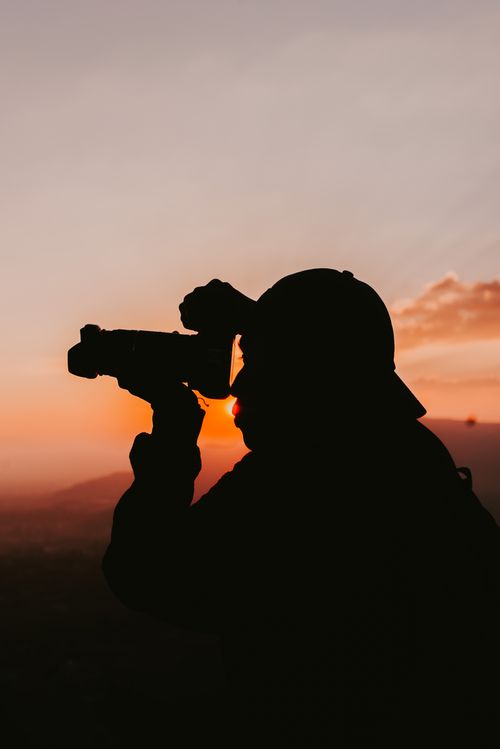 Free A silhouette of a photographer taking a picture against a vibrant sunset sky. Stock Photo