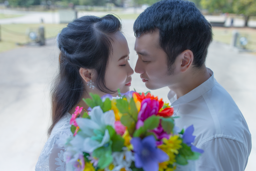 Tender moment between a bride and groom sharing an intimate gaze with a vibrant bouquet.