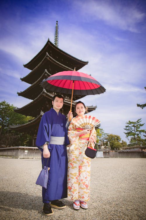 A Couple Wearing Traditional Kimonos with an Umbrella and a Hand Fan