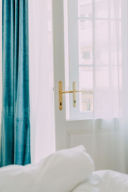 Inviting sunlight streaming through an open door with white curtains and blue drapes.