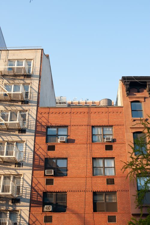 Free Red brick and white concrete building facade with fire escapes on a sunny day. Stock Photo