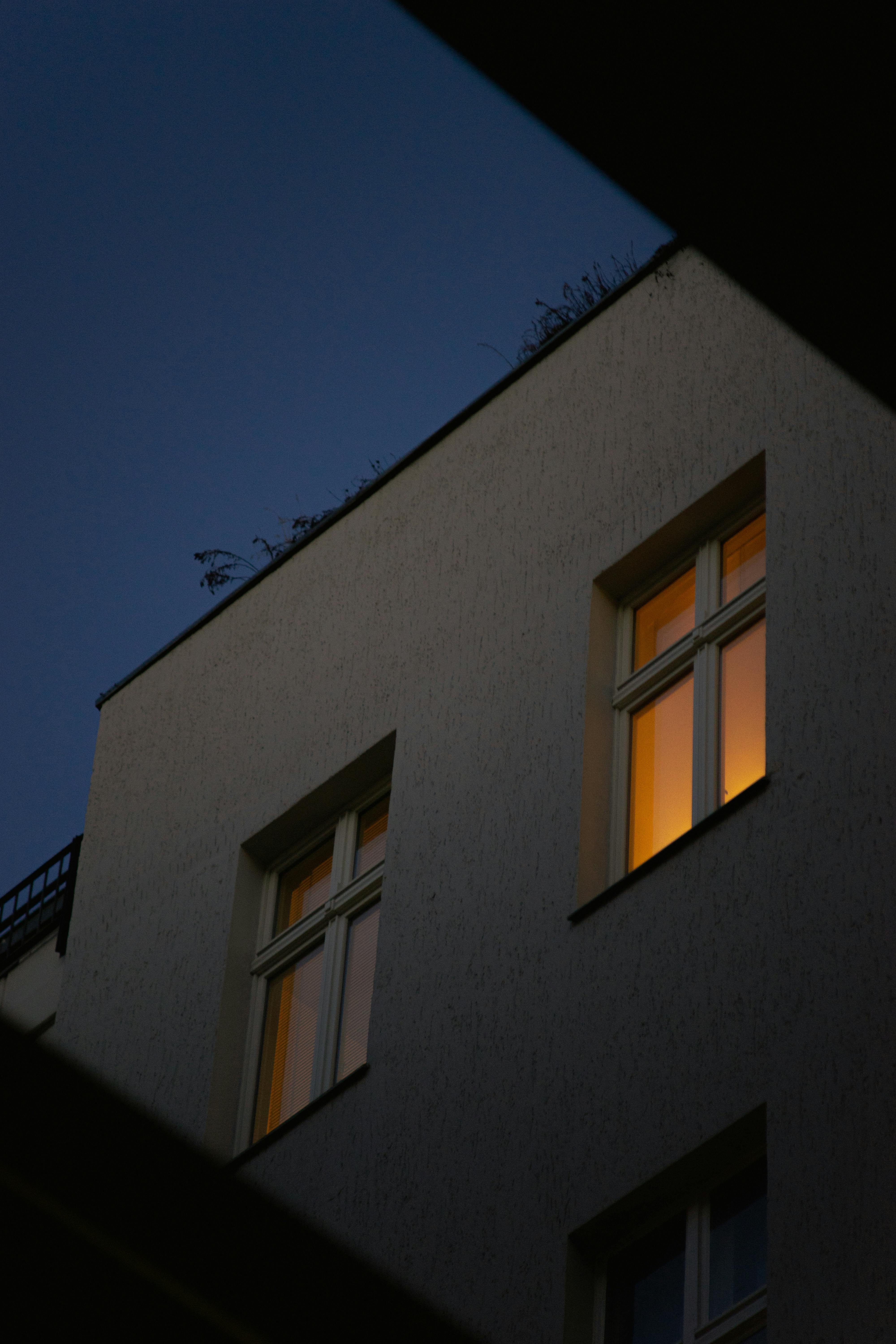 Low-angle shot of a modern building with warm-lit windows at night.
