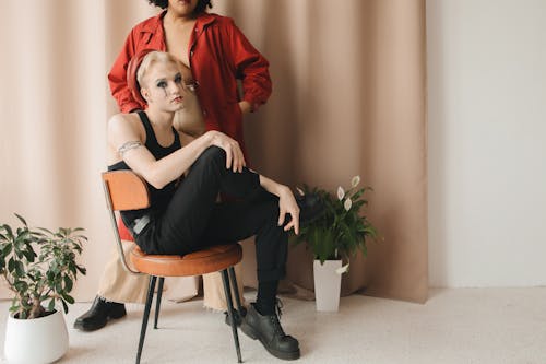 A Person in Black Tank Top Sitting on a Chair Beside a Person in Red Jacket