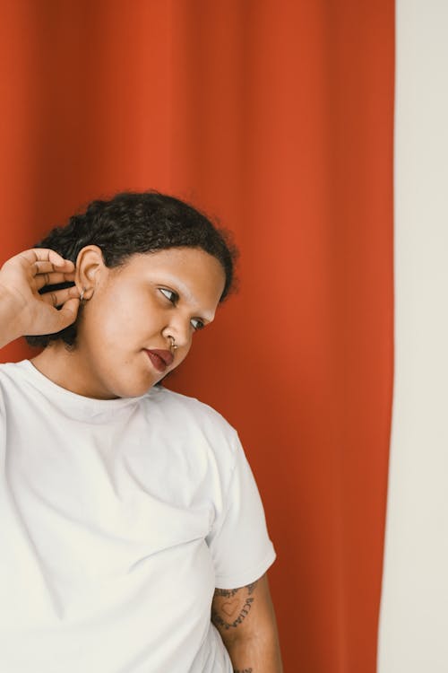 Woman in White Crew Neck Shirt Near Red Curtain