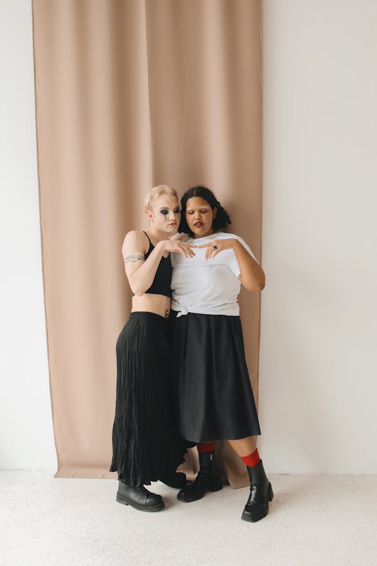 Women In Black Skirts Standing Close Together Beside Beige Curtain