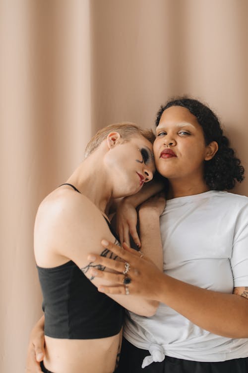 A Woman in White Shirt Embracing Her Tattooed Friend