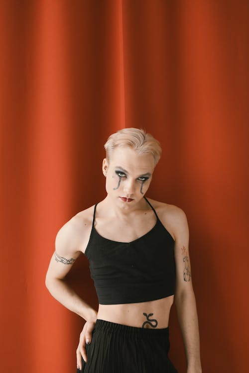 Person with Tattoos and Creative Makeup Posing on Red Background 