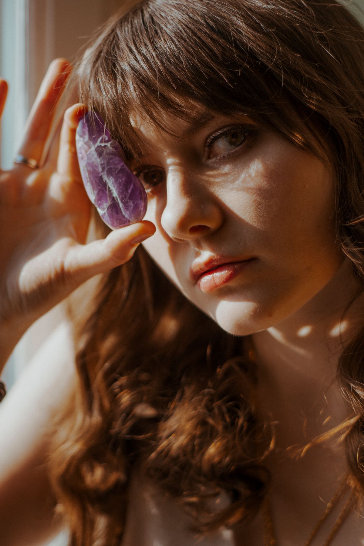 Woman holding a deep purple amethyst stone in natural daylight