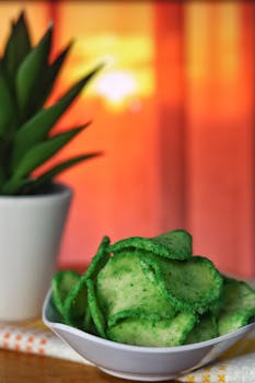 Enjoy a bowl of vibrant green chips in a cozy setting with a warm sunset backdrop.