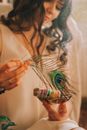 Crop content female with wavy dark hair and smudge sticks with smoke on blurred background