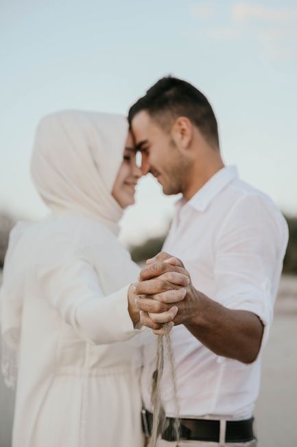Side view of positive Muslim female in white dress and hijab dancing with boyfriend in nature in daytime