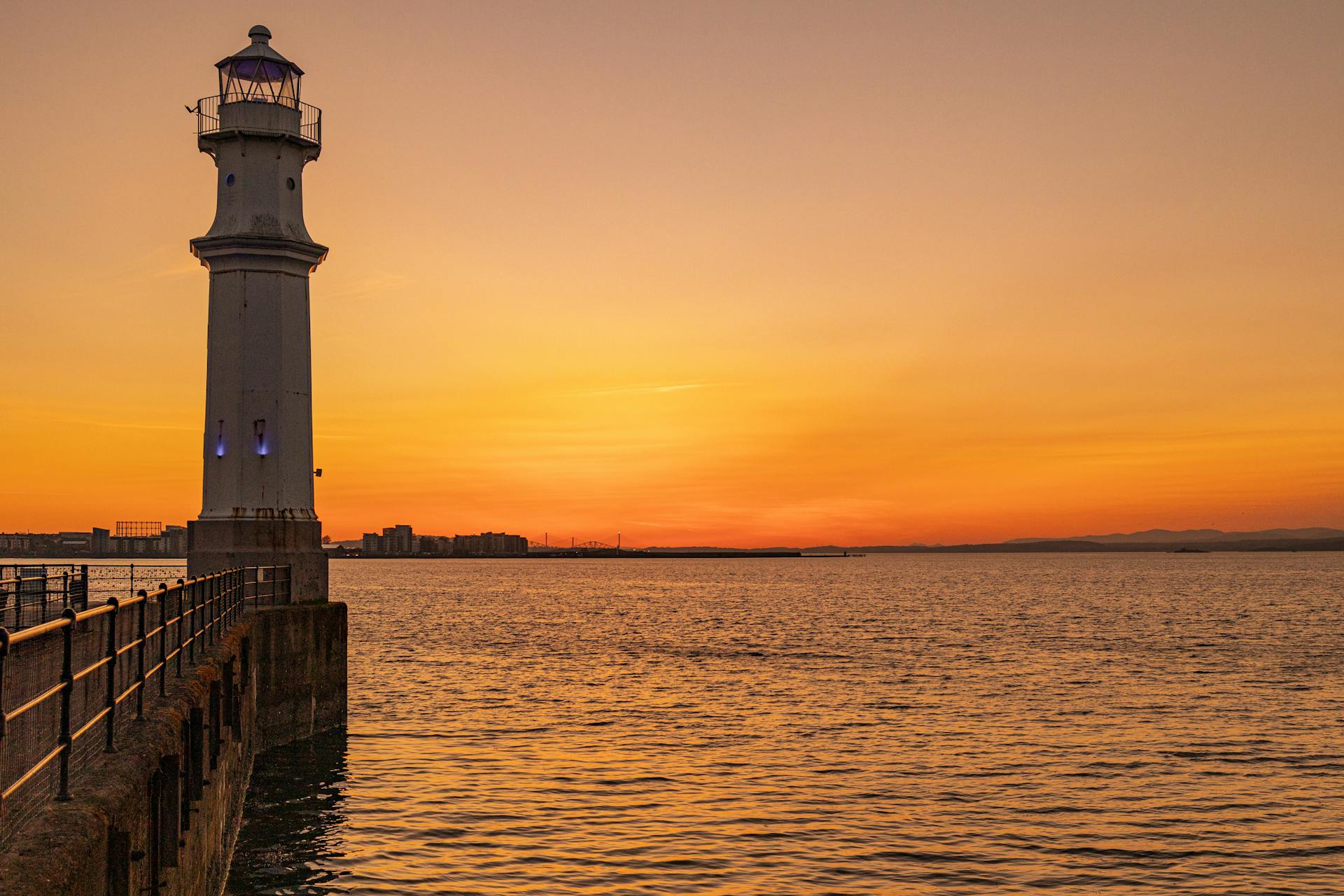 Beautiful sunset view of Newhaven Lighthouse by the ocean in the UK.