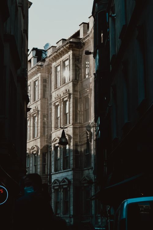 Free A dramatic urban scene capturing historic architecture and deep shadows in the city alley. Stock Photo