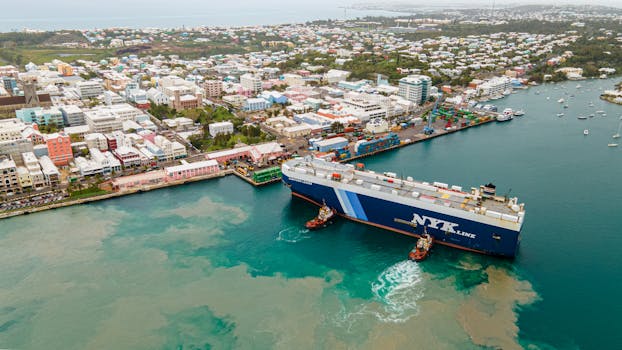 Aerial perspective of a cargo ship docking in Bermuda's vibrant port area.