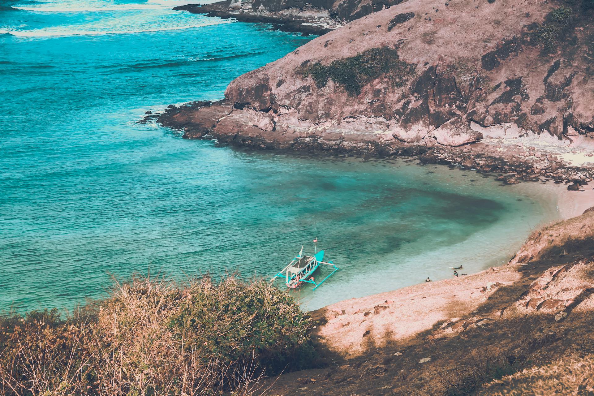 A tranquil tropical cove in Indonesia with a boat near the shore and turquoise waters, ideal for travel and tourism.