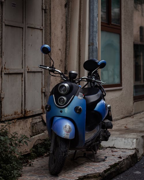 Blue and Black Moped Parked on Sidewalk