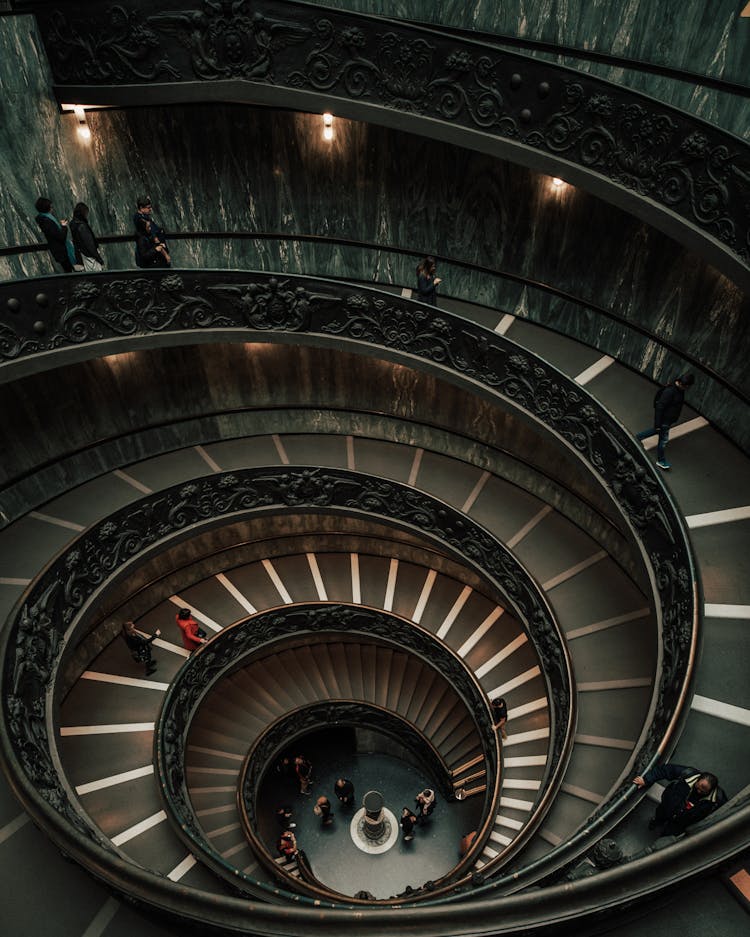 People Walking On Concrete Spiral Staircase