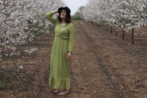 Woman in Green Long Sleeve Dress Standing on Flower Field