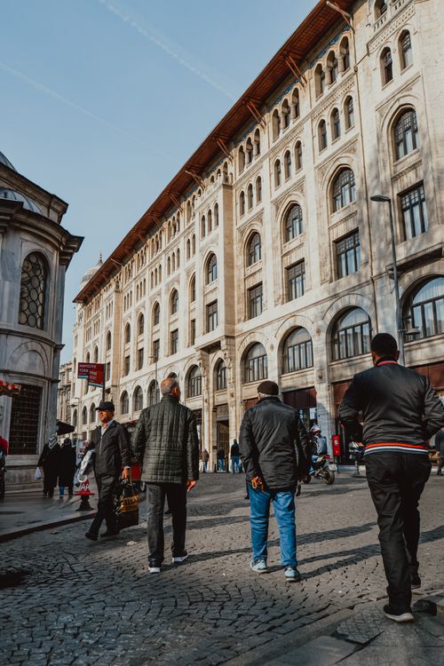 Free View of people walking by a historic building on a cobblestone street, capturing urban life. Stock Photo