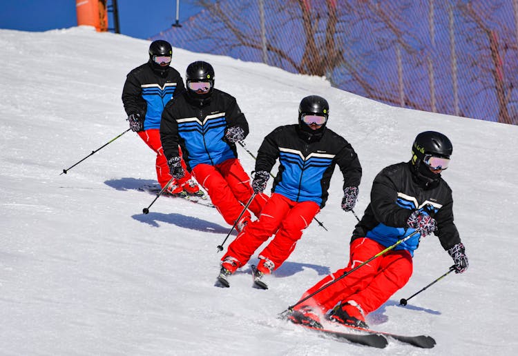 A Team Of Skiers In Uniform Skiing Downhill