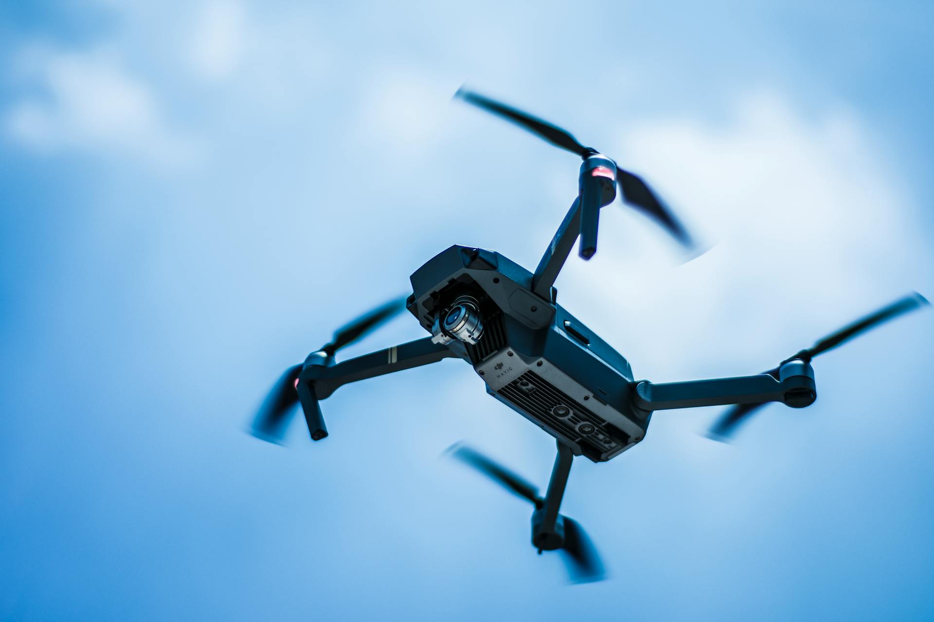 A sleek drone captures the sky in action with a clear blue background, showcasing modern technology.