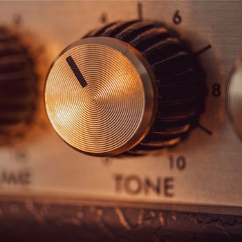 Macro image of a vintage amplifier tone knob with intricate detail.