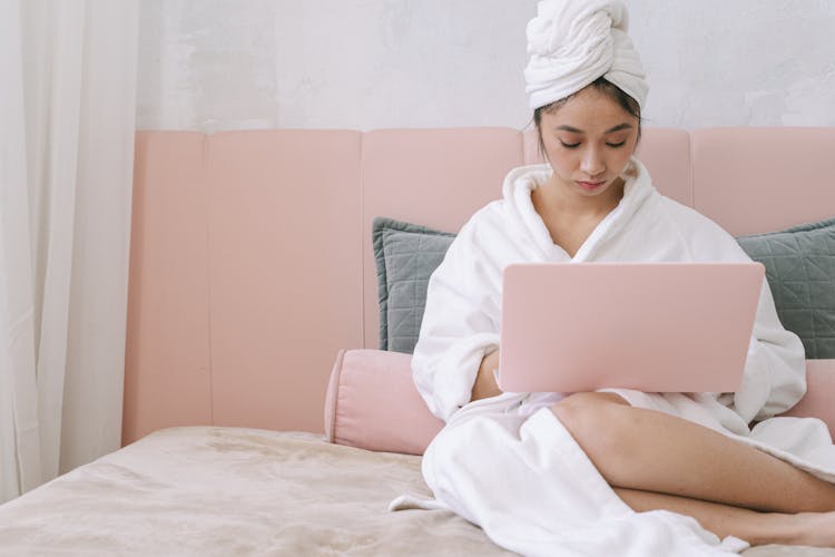 A Woman In A Bathrobe Using A Laptop