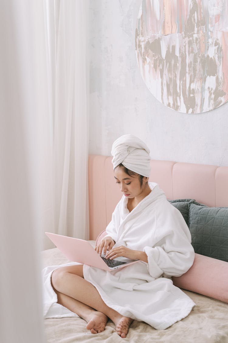 A Woman In Her Bathrobe Using A Laptop