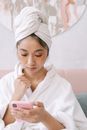 Woman in White Robe Holding Pink Smartphone