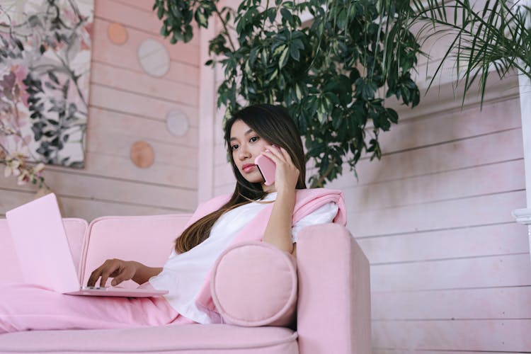 A Low Angle Shot Of A Woman Sitting On The Couch While Talking On The Phone