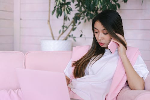 A Woman in White Shirt Working while Talking on the Phone