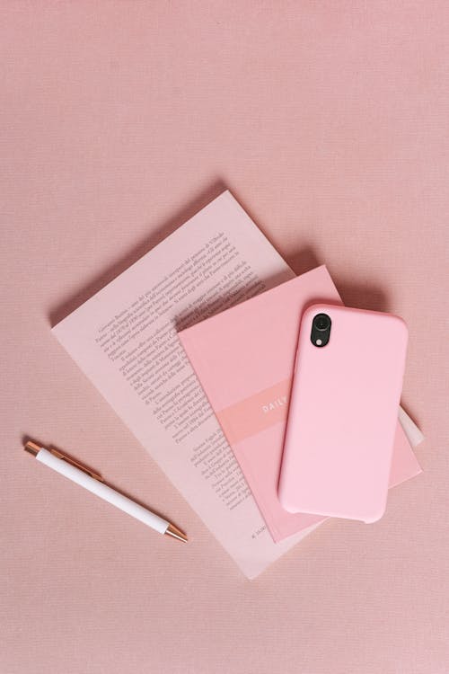 Immagine gratuita di libri, smartphone, superficie rosa