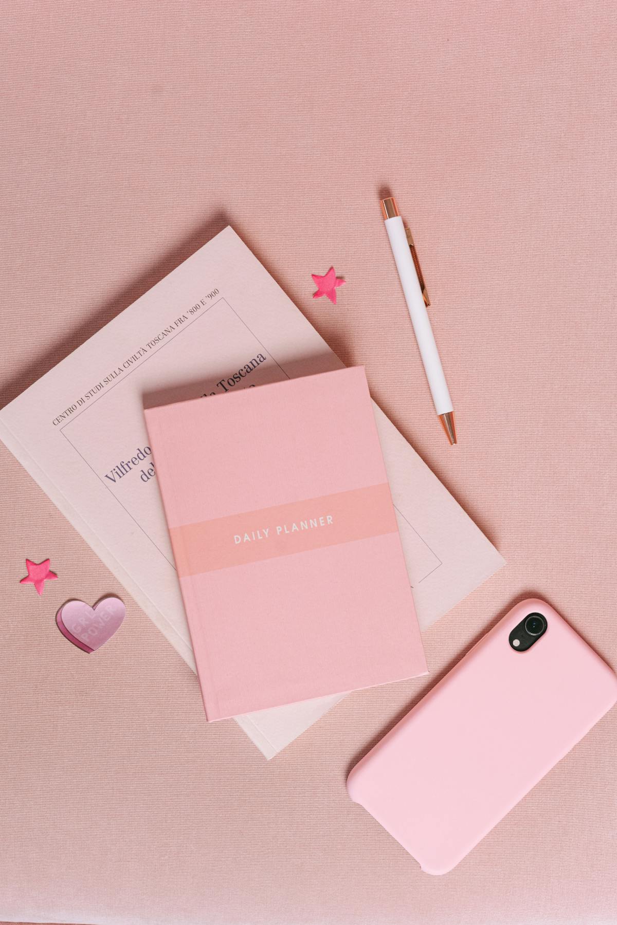 Planner rosa e smartphone affiancati in flat lay per pianificazione